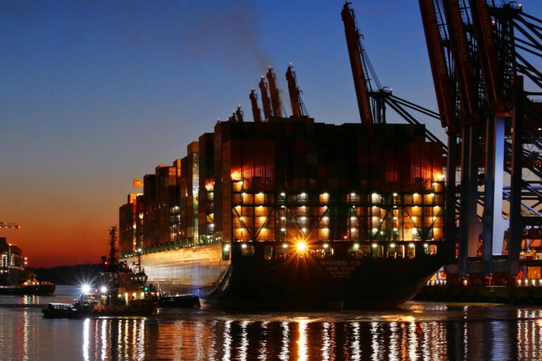 A container ship docked at Hamburg port illuminated by sunset reflections on the river Elbe.